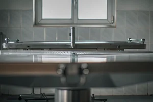 Hydraulic embalming table with a stainless steel surface and drainage system.