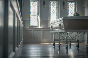 Funeral home chapel interior with a polished church truck on hardwood floor, warm wood tones, soft natural light